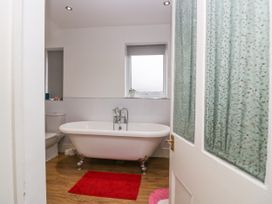 A bathroom with a clawfoot bathtub a toilet and a red bath mat at 7 New Street in Sedbergh