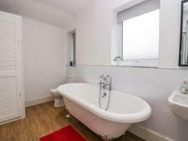 A bathroom with a freestanding bathtub a toilet a sink a window and a red rug at 7 New Street in Sedbergh