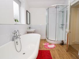 A bathroom with a bathtub shower enclosure sink and red and pink mats at 7 New Street in Sedbergh