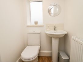 A bathroom with a toilet sink mirror window and a trash bin at 7 New Street in Sedbergh