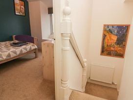 A bedroom with a bed and dresser next to a staircase with a framed picture above a radiator at 7 New Street in Sedbergh