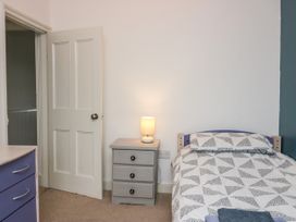 A bedroom with a single bed a bedside table with a lamp and a dresser at 7 New Street in Sedbergh