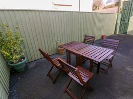 An outdoor seating area with wooden table and chairs at No.22 The Clicketts Tenby
