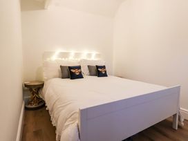 A bedroom with a white bed and pillows with bee designs and a rustic bedside table at Bee Cottage in Ottinge near Lyminge