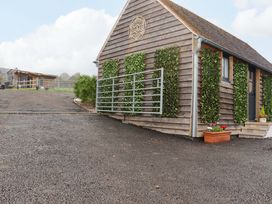A small wooden building with green plants on the walls and a metal gate at Bee Cottage in Ottinge near Lyminge