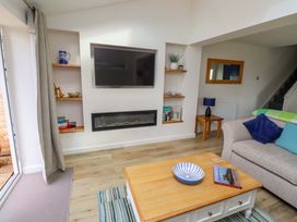 A living room with a television and a coffee table at Lavender Cottage in Beadnell