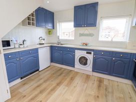 A kitchen with blue cabinets and a washing machine at Lavender Cottage Beadnell