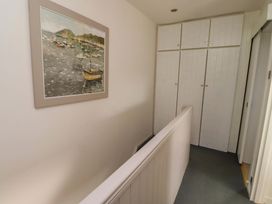 A hallway with a painting and storage cabinets at Lavender Cottage Beadnell