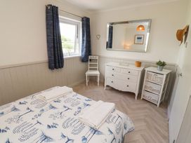 A bedroom with a bed and dresser at Lavender Cottage Beadnell