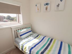 A bedroom with a bed and window at Lavender Cottage Beadnell