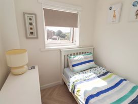 A bedroom with a bed and lamp at Lavender Cottage in Beadnell