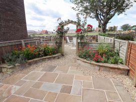 A garden with flowerbeds and an archway at Lavender Cottage in Beadnell