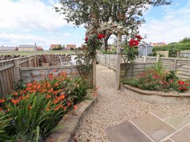 A garden with a pathway and flowers at Lavender Cottage Beadnell