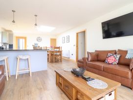A living room with a sofa and dining area at Bryn Bras in Corwen