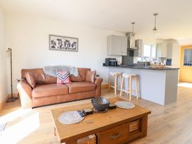 A living room with a sofa and kitchen counter at Bryn Bras in Corwen