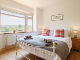 A bedroom with a bed and windows overlooking a landscape at Bryn Bras in Corwen
