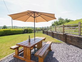 A wooden table and benches with an umbrella in a garden at Bryn Bras Corwen