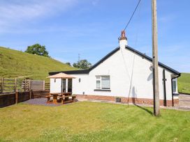 An outdoor area with a house and patio table at Bryn Bras in Corwen