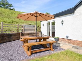 An outdoor area with a wooden table and umbrella at Bryn Bras in Corwen