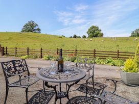 An outdoor seating area with a table and chairs overlooking a field with sheep at Bryn Bras Corwen