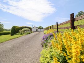 A house with flowers along a gravel road at Bryn Bras in Corwen