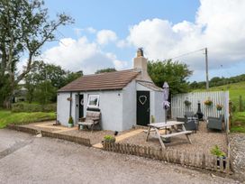 A cottage with a bench and table outside at High Wreah Bolt Hole in Cleator Moor