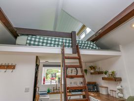 A kitchen with a loft bed above and a ladder at High Wreah Bolt Hole in Cleator Moor