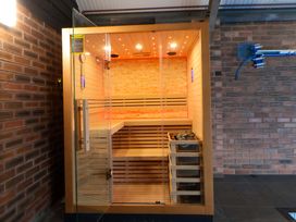 A sauna with wooden benches and a glass door at Home Farm St Asaph