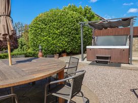 A garden with an outdoor table and chairs and a hot tub at Home Farm St Asaph