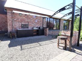 An outdoor kitchen setup with a barbecue grill and seating at Home Farm St Asaph