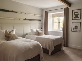 A bedroom with two beds and rowing oars on the wall at Lower Well Farm House in Totnes