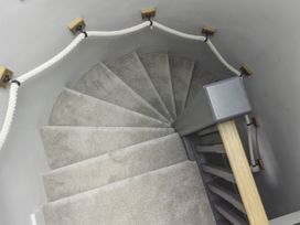 A spiral staircase with a carpet and handrail at Lower Well Farm House in Totnes