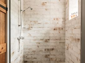 A shower with a wall-mounted shower head and soap dispenser at Lower Well Farm House in Totnes