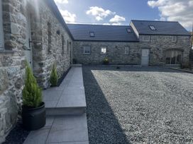 An outdoor area with stone buildings and a gravel path at Beudy Tanrallt in Llanfachraeth