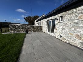 An outdoor area with a stone wall and sliding doors at Beudy Tanrallt in Llanfachraeth