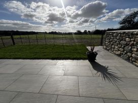 A garden with grass and paving stones at Beudy Tanrallt in Llanfachraeth