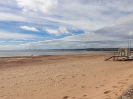 A beach with a lifeguard station and a person walking at Sea Lovers in Exmouth