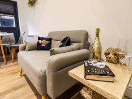 A seating area with a grey sofa, cushions, a table with a book, a bottle of prosecco and glasses at Kingfisher Cottage Ottinge near Lyminge