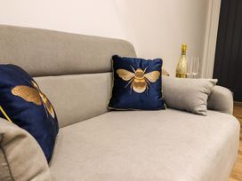 A beige sofa with two blue cushions embroidered with bees and a bottle with two glasses on a side table at Kingfisher Cottage in Ottinge near Lyminge