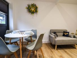 A dining area with a round table set for four and a small sofa with cushions in a room at Kingfisher Cottage Ottinge near Lyminge