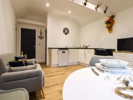 A kitchen and dining area with a sofa table dishes and a television at Kingfisher Cottage in Ottinge near Lyminge