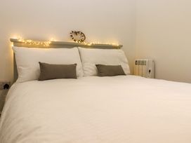 A bed with white bedding and gray pillows in a bedroom with fairy lights on the headboard at Kingfisher Cottage Ottinge near Lyminge