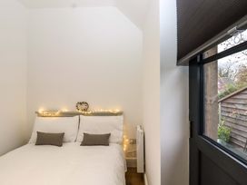 A bedroom with a bed with white bedding and two gray pillows next to a window with a black blind at Kingfisher Cottage in Ottinge near Lyminge