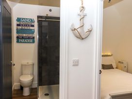 A bathroom with a toilet and glass shower next to a bedroom with a bed and pillow at Kingfisher Cottage in Ottinge near Lyminge