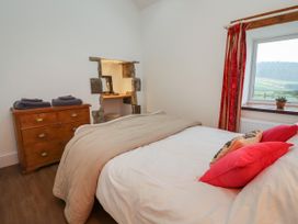 A bedroom with a bed a dresser and a window with red curtains at The Old Parlour in Cwm near Dyserth