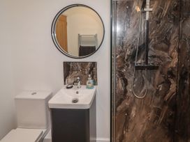 A bathroom with a toilet sink mirror and a shower with marble walls at The Old Parlour in Cwm near Dyserth