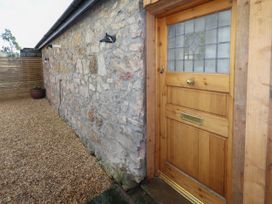 A wooden door with stained glass set in a stone wall next to a gravel pathway at The Old Parlour in Cwm near Dyserth