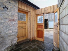 A stone wall with a wooden door and an open wooden gate leading to an outdoor area at The Old Parlour in Cwm near Dyserth