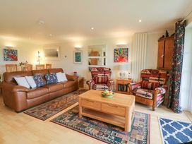 A living room with a sofa, armchairs, and a coffee table at 5 Thurlestone Beach Thurlestone
