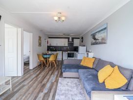 A living room with a sofa and dining area at Shells Cottage in Looe